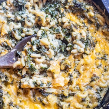 a spoon scooping some mac and cheese with kale.