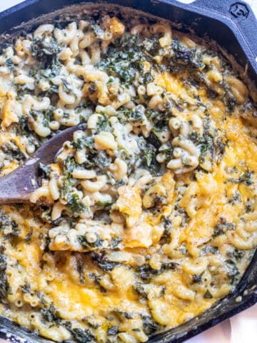 a spoon scooping some mac and cheese with kale.