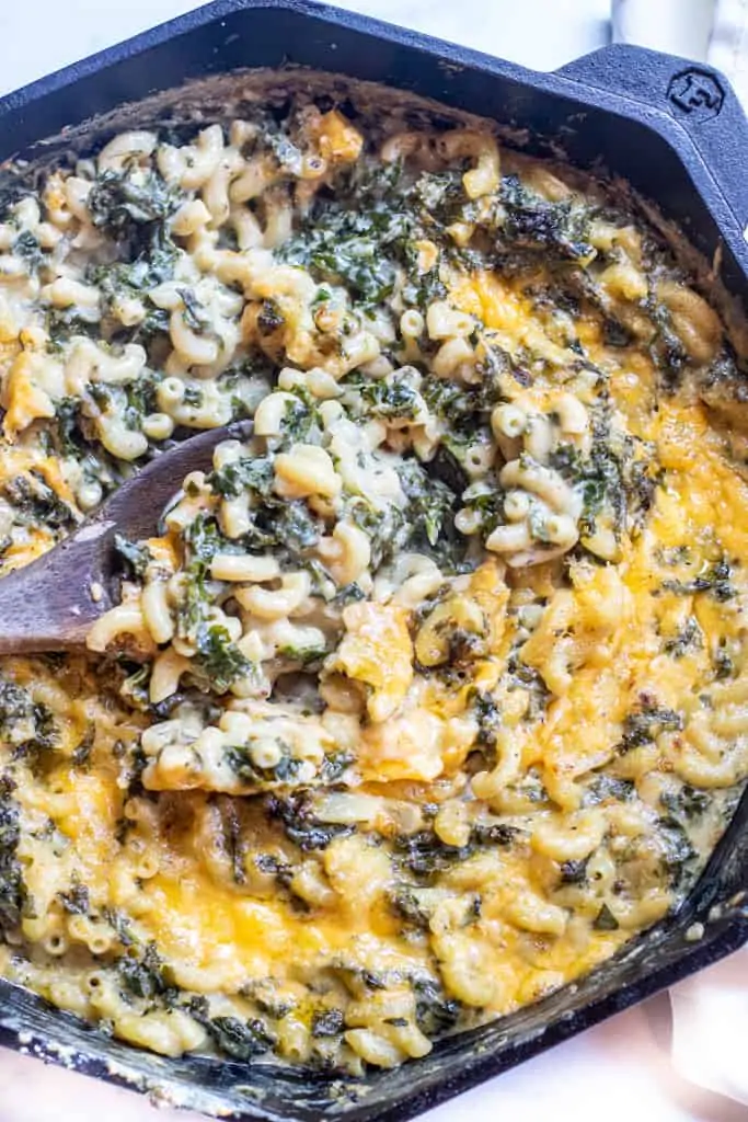 a spoon scooping some mac and cheese with kale.