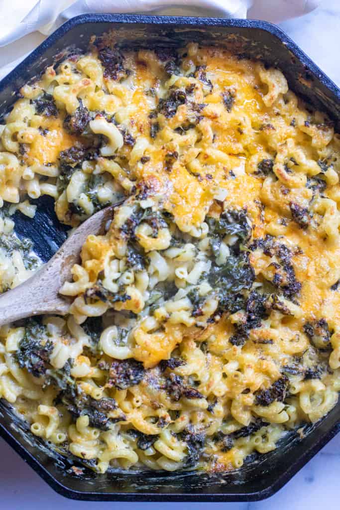 a spoon scooping some mac and cheese with kale.