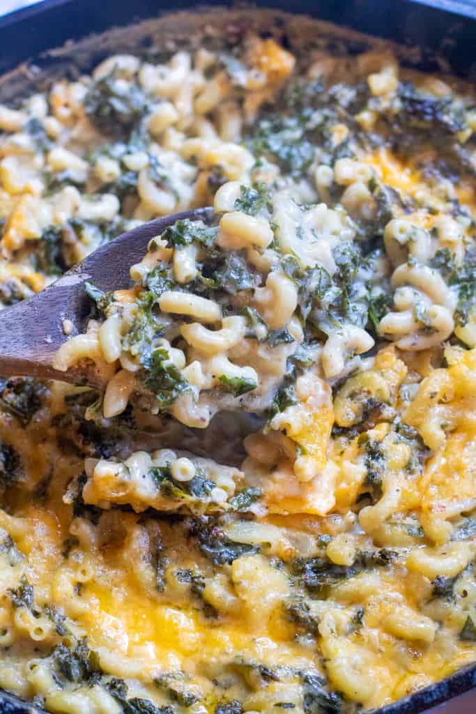 a spoon scooping some mac and cheese with kale.