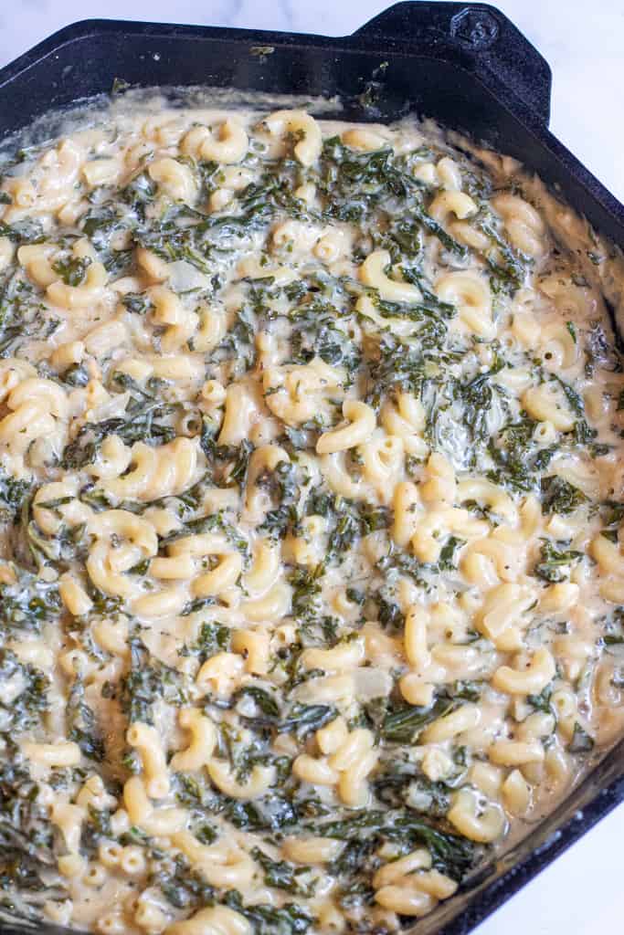 creamy mac and cheese with kale in a cast iron.