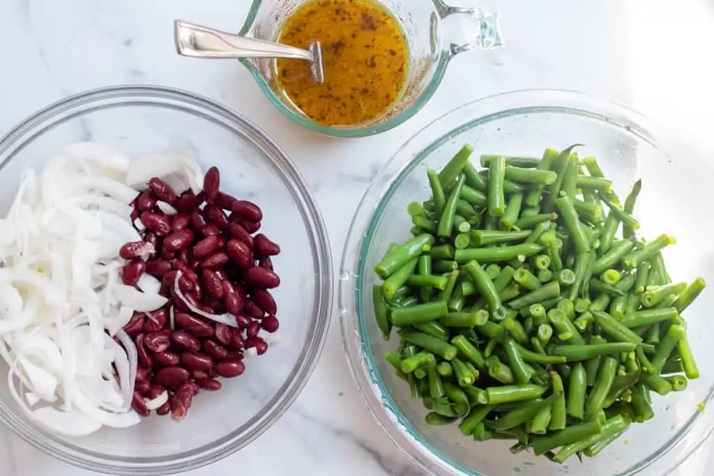 dressing in a pyrek, bowl of onions and beans, and bowl of green beans.