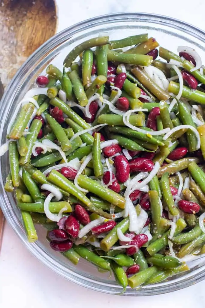 a bowl of fresh green beans, kidney beans, and onions.