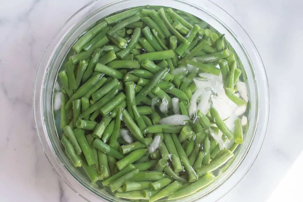 blanched green beans in a bowl of ice.