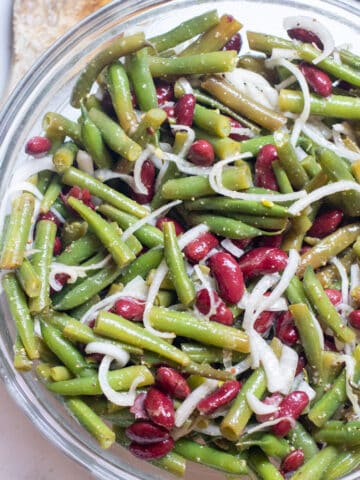 a bowl of fresh green beans, kidney beans, and onions.