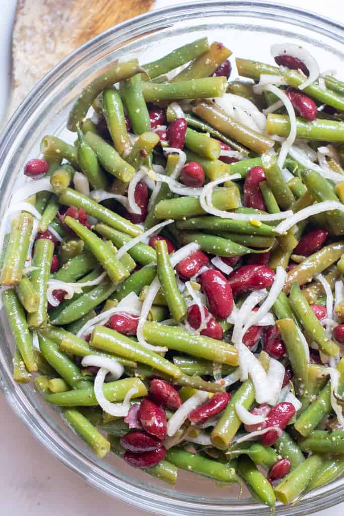 a bowl of fresh green beans, kidney beans, and onions.