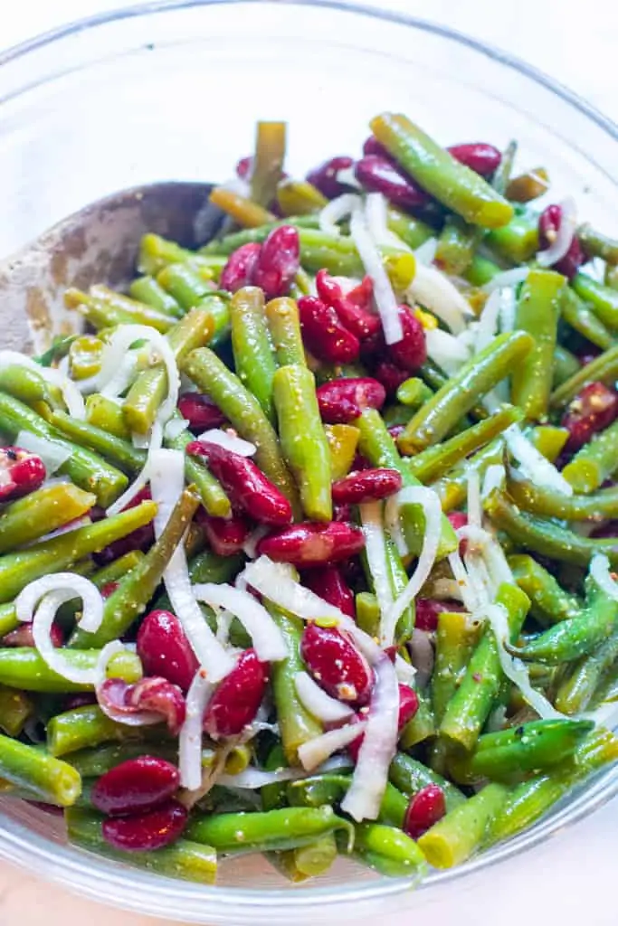 a large bowl with wooden spoon and bean and onion salad.