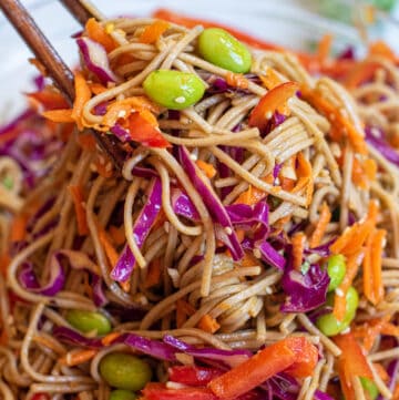 chopsticks holding up a soba noodle salad.