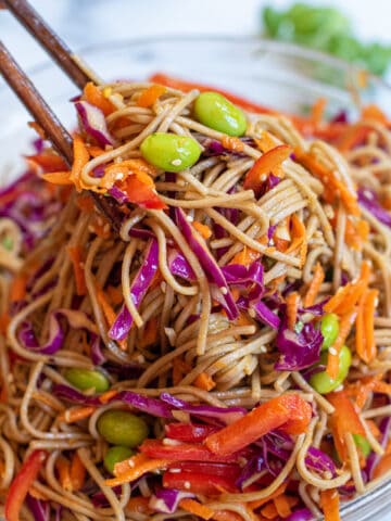 chopsticks holding up a soba noodle salad.