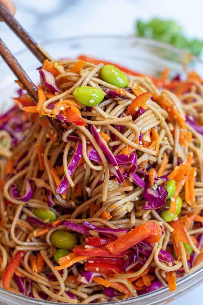 chopsticks holding up a soba noodle salad.