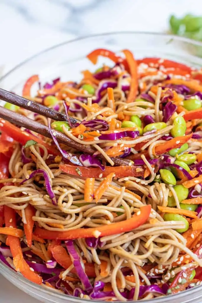 chopsticks holding up a soba noodle salad.