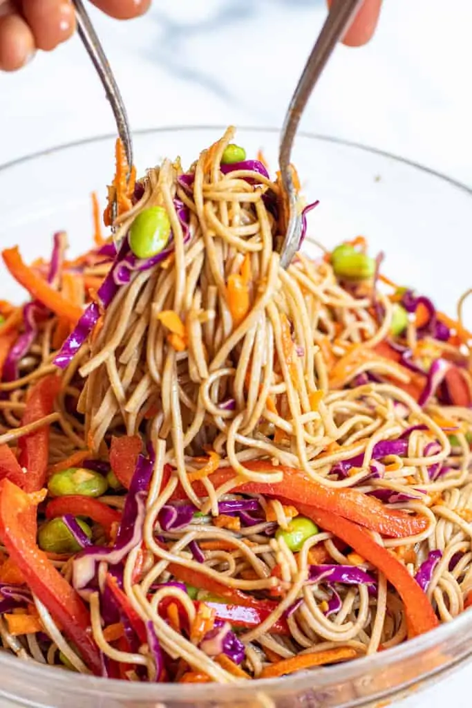 spoons mixing soba noodle salad.