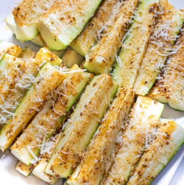 a plate of baked zucchini fries with cheese.