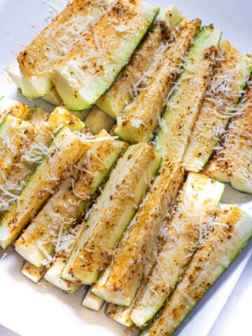 a plate of baked zucchini fries with cheese.