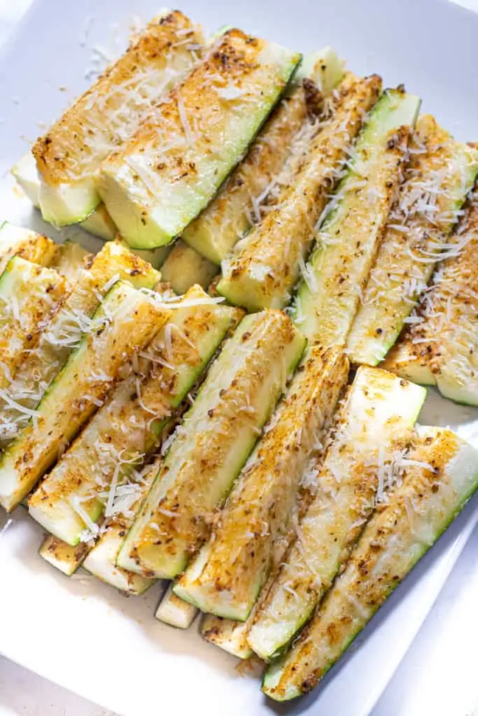 a plate of baked zucchini fries with cheese.