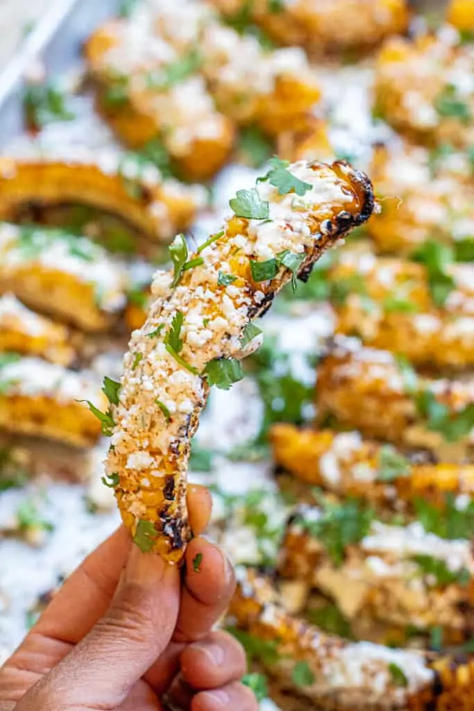 a hand holding up a Mexican street corn ribs.