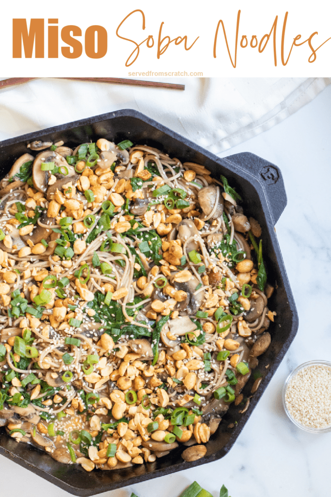 cast iron of noodles with spinach, mushrooms, topped with peanuts and scallions with Pinterest pin text.