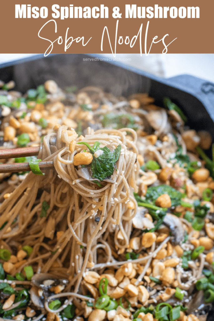 cast iron of noodles with spinach, mushrooms, topped with peanuts and scallions chopsticks holding up noodles with Pinterest pin text.
