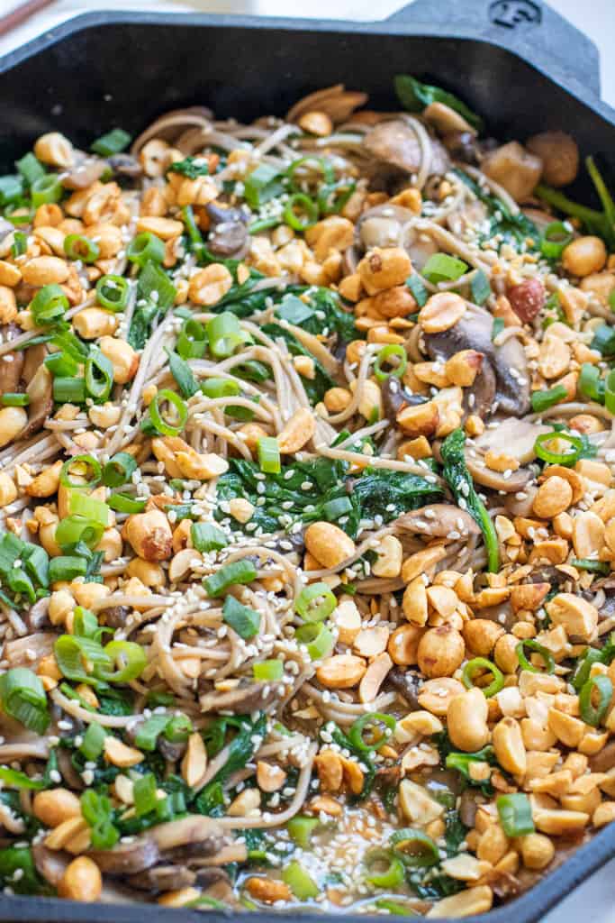 cast iron of noodles with spinach, mushrooms, topped with peanuts and scallions.