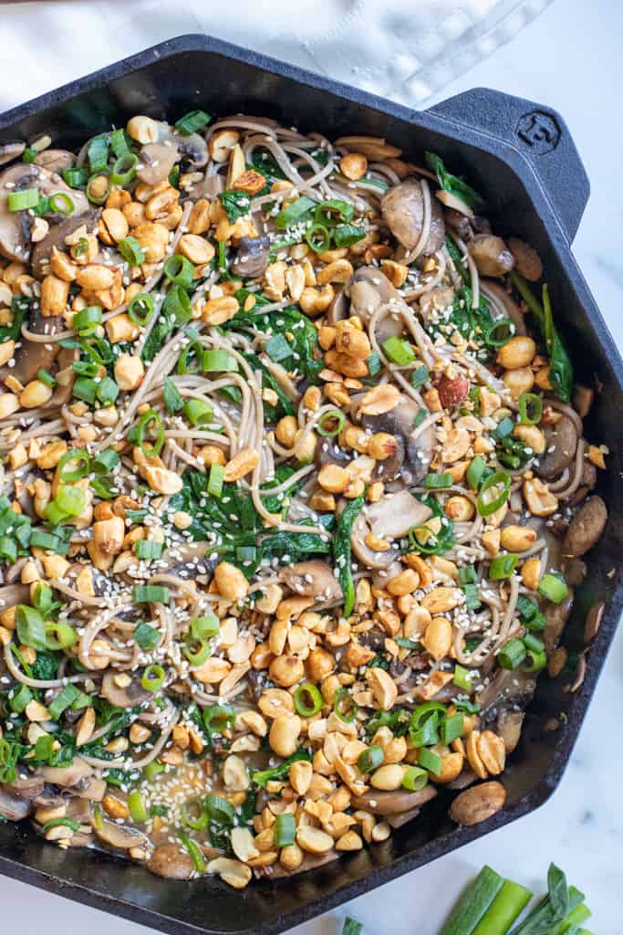 cast iron of noodles with spinach, mushrooms, topped with peanuts and scallions.