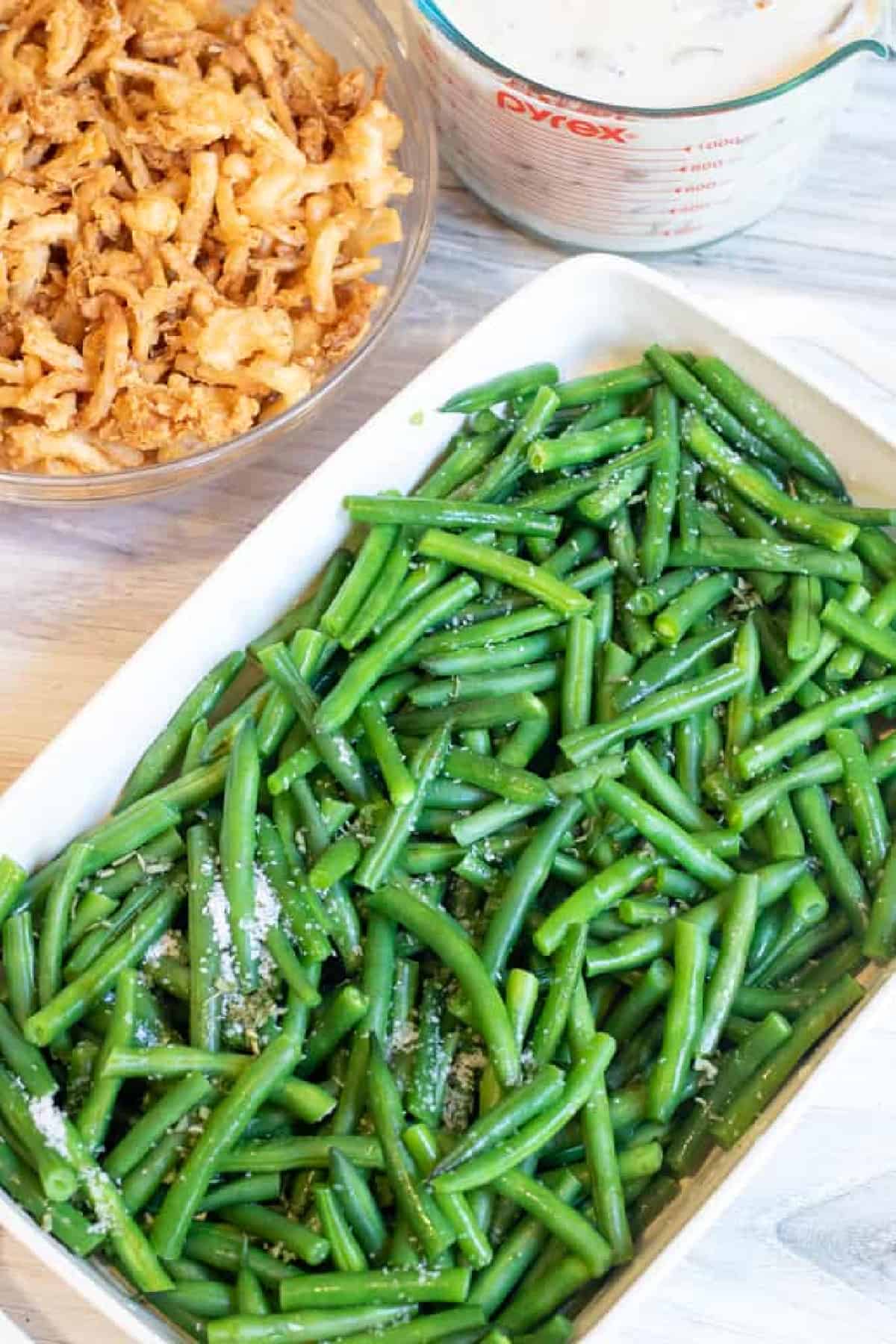 fresh green beans in a dish next to mushroom soup and fried onions.