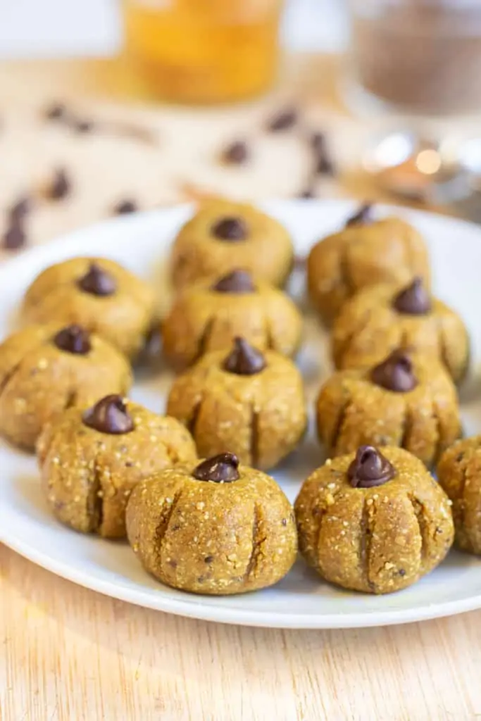 a plate of pumpkin shaped bliss balls topped with chocolate chips.