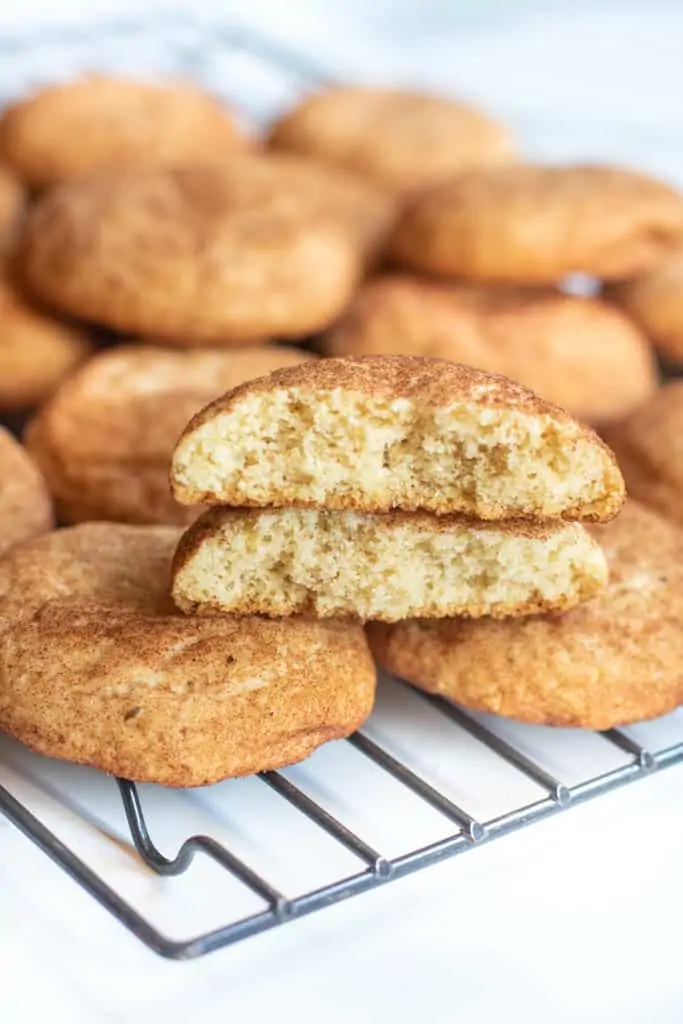 split in half snickerdoodle stacked on a cooling rack of cookies.