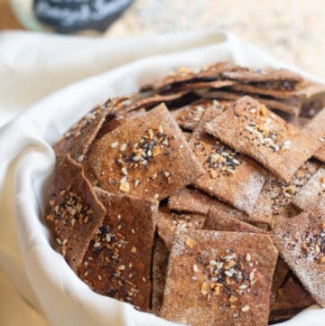 a bowl of crispy crackers with everything bagel toppings.