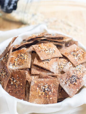 a bowl of crispy crackers with everything bagel toppings.