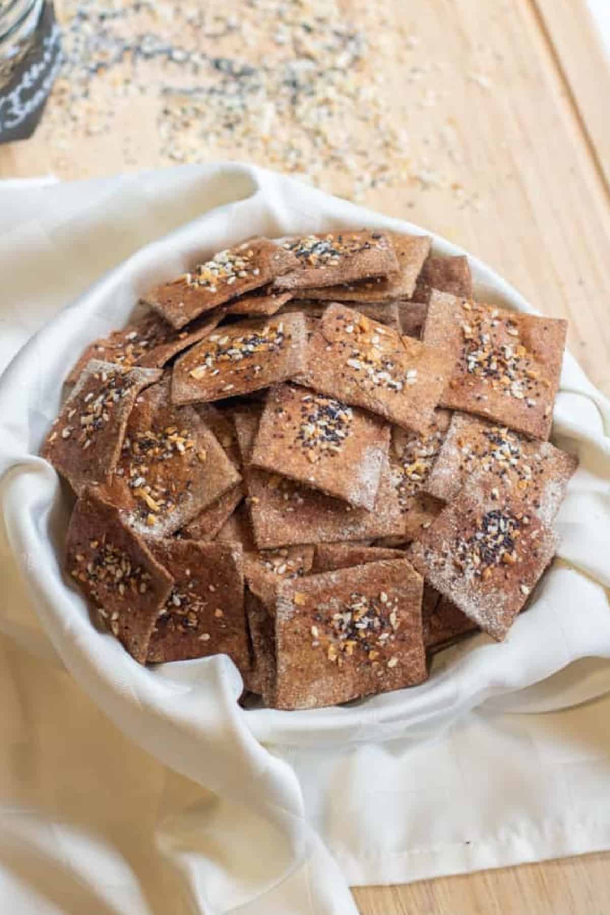 a bowl of crispy crackers with everything bagel toppings.