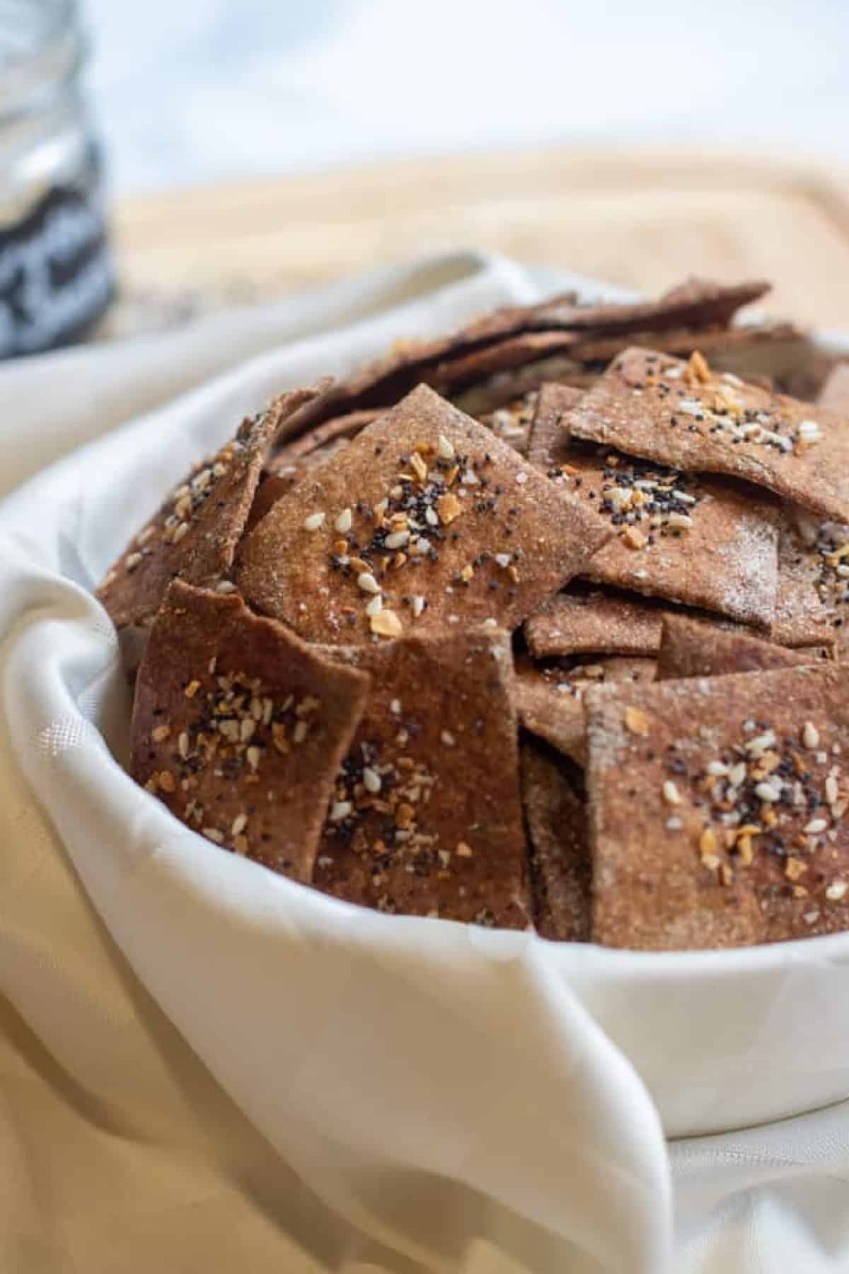a bowl of crispy crackers with everything bagel toppings.