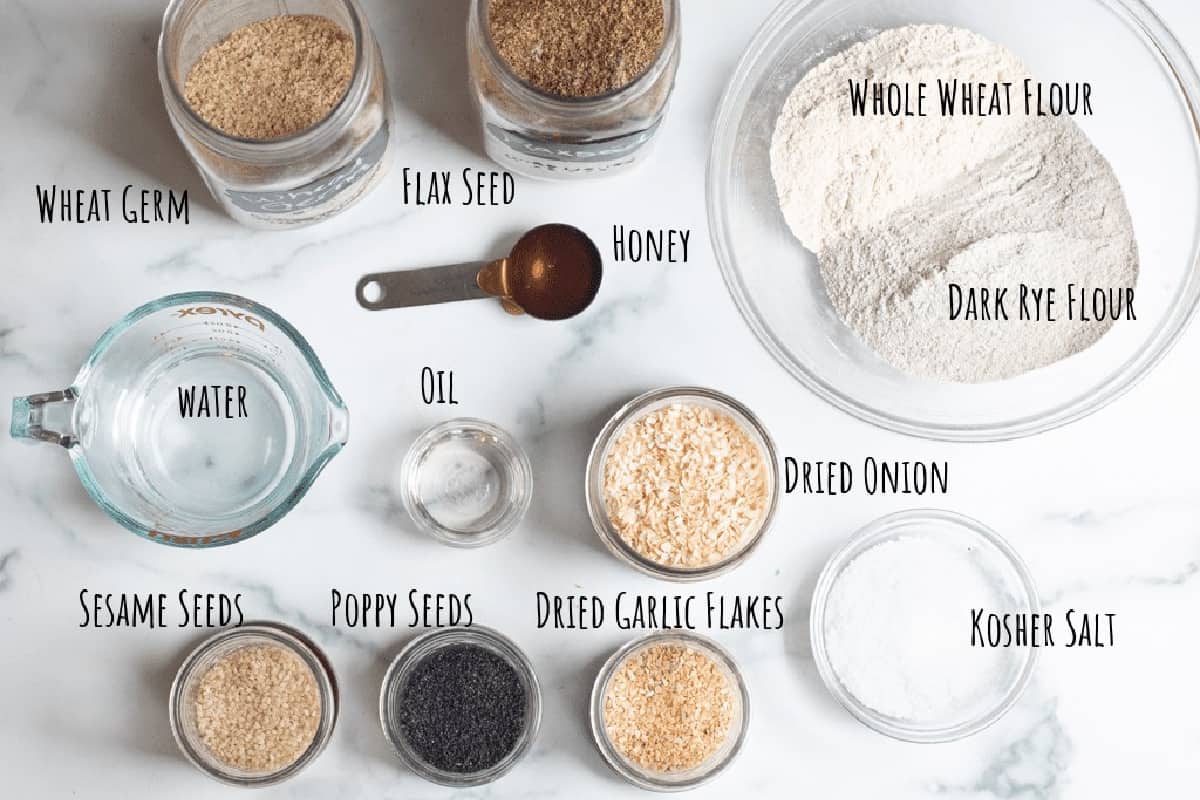 jars of flax seed, wheat germ, a bowl of flours, jars of everything bagel seasoning ingredients, salt, and water.