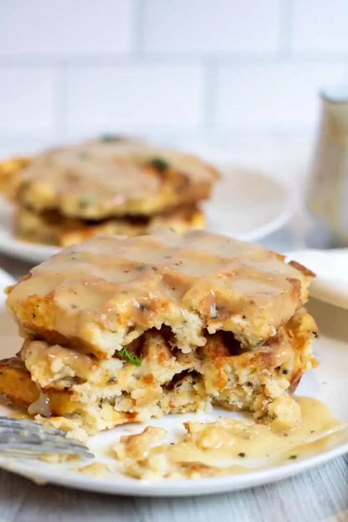 stacked gravy topped waffles with a forkful taken out.