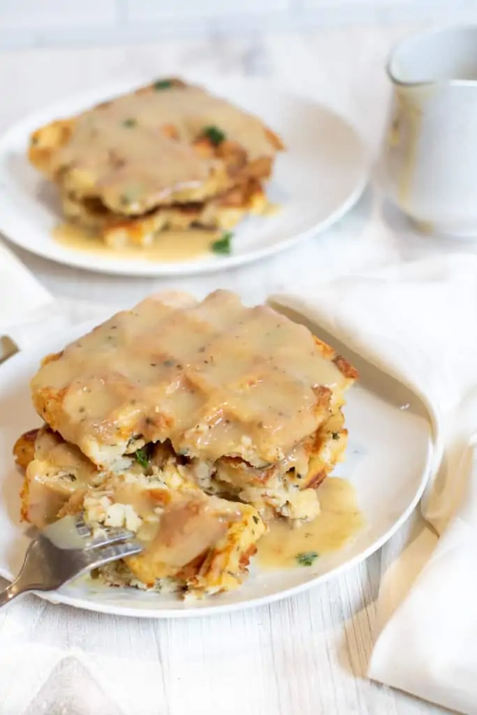 waffles topped with gravy with a fork taking a bite out.