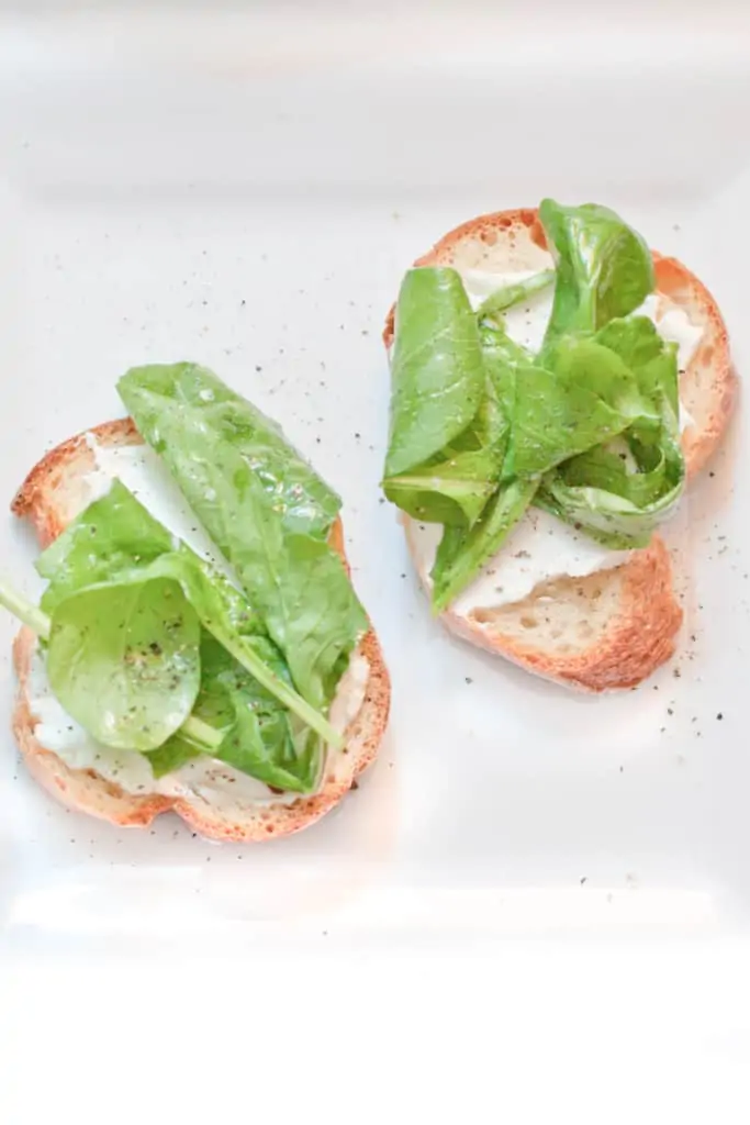 crostini topped with whipped cheese and arugula.