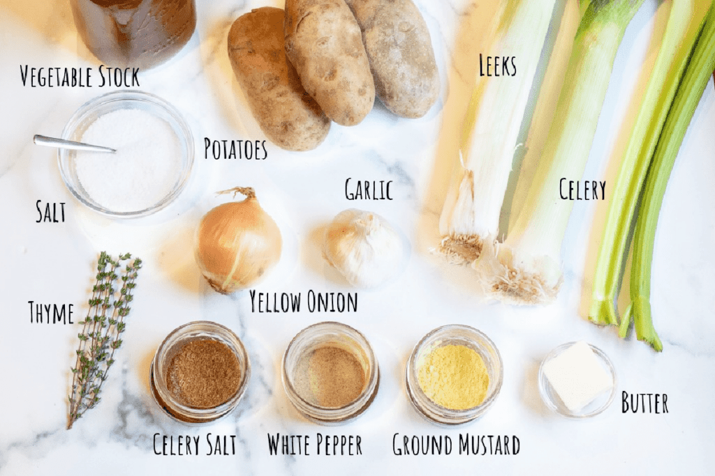 stock, leeks, potatoes, celery, thyme, onions, garlic, spices, and butter on a counter.