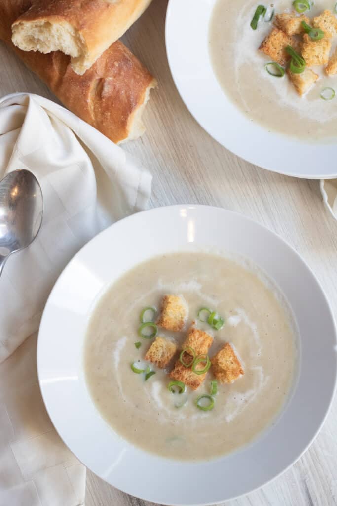 a bowl of soup topped with croutons and green onions.