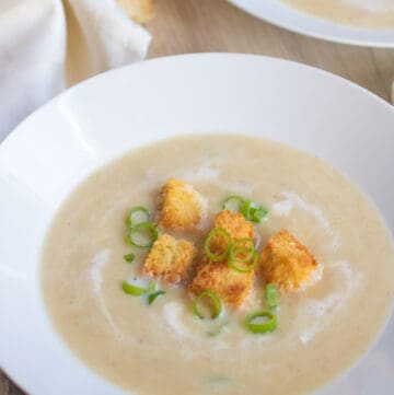 a bowl of soup topped with croutons and green onions.