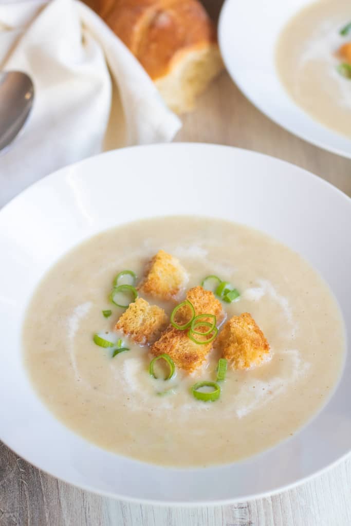 a bowl of soup topped with croutons and green onions.