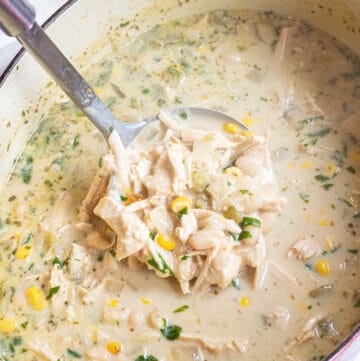 a dutch oven with white chili and a ladle with a scoop.