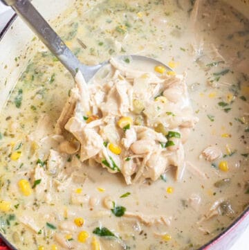 a dutch oven with white chili and a ladle with a scoop.