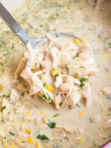 a dutch oven with white chili and a ladle with a scoop.