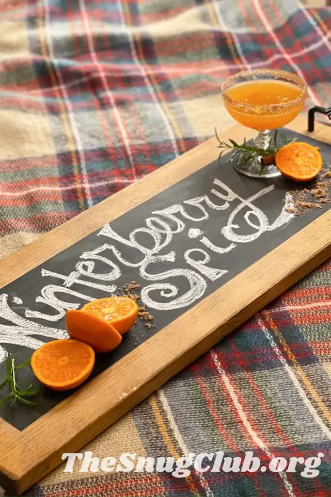 a cocktail on a board that says winterberry spice.