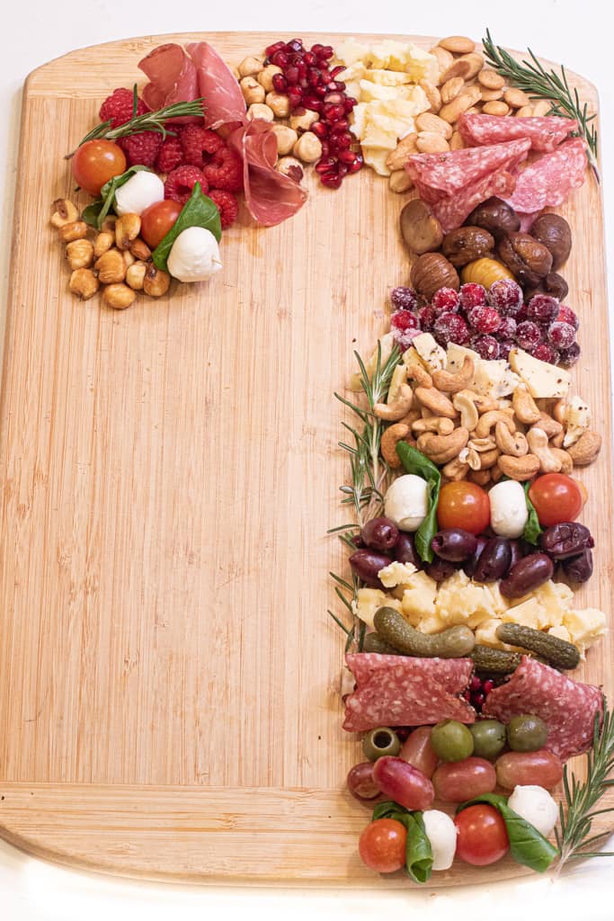 a candy cane shaped meat, cheese, and fruit and nut board.