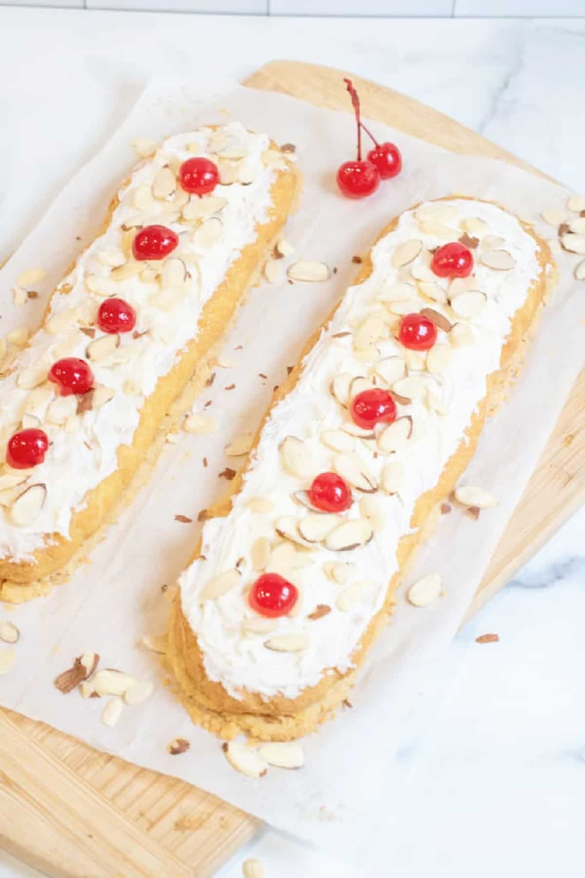 two strips of frosted pastries with sliced almonds and cherries on top.