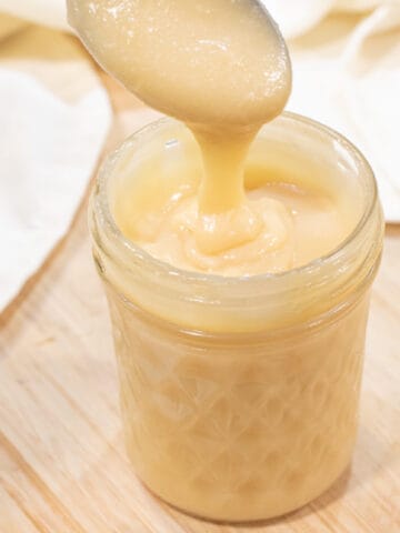 an open mason jar of condensed milk with a spoon.