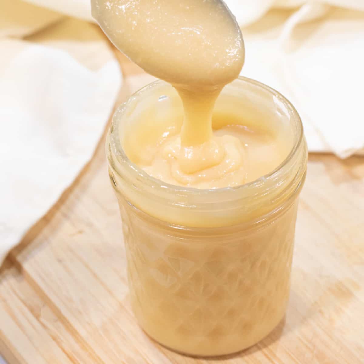 an open mason jar of condensed milk with a spoon.