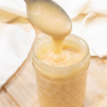 an open mason jar of condensed milk with a spoon.