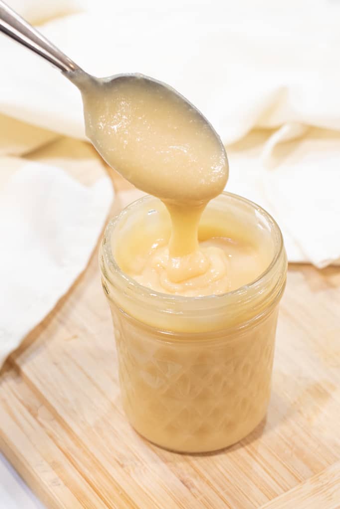 an open mason jar of condensed milk with a spoon.
